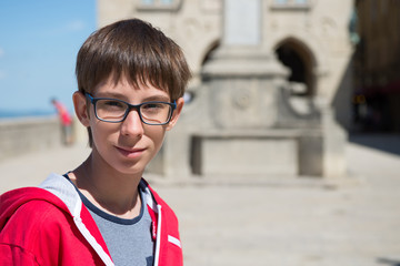 Young boy spectacled looking at camera outdoor over San Marino city-state. Vision, eyesight, sight,...