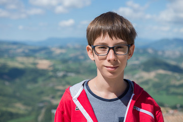 Young boy spectacled looking at camera outdoor over San Marino city-state. Vision, eyesight, sight,...