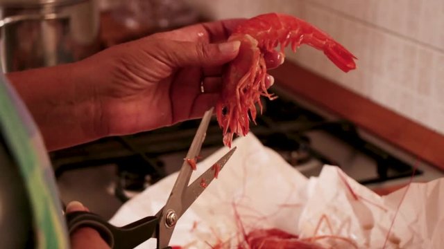 La cuoca in cucina pulisce i gamberi