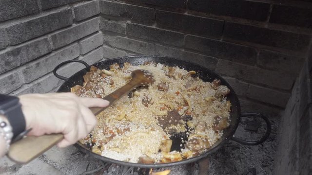 Cooking Spanish paella, a famous typical spanish rice dish. Adding and stiring until the rice starts being a bit cooked