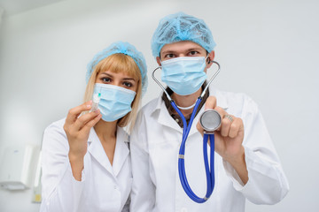 Two doctors with the masck, stethoscope in hand and injection