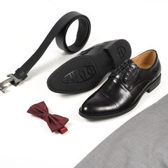 Close up of modern man accessories. Bordeaux bow tie, leather shoes, belt on white  background. Set for formal style of wearing isolated on white background..