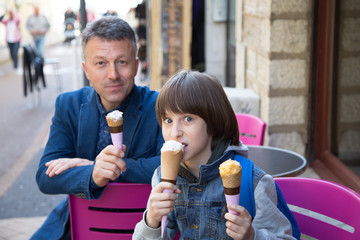 Father and son eating ice-cream in street cafe, family lifestyle. Dad with ofspring enjoying icecream spring outdoor