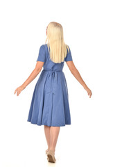 full length portrait of blonde girl wearing blue dress. standing pose with back to the camera. isolated on white  studio background.