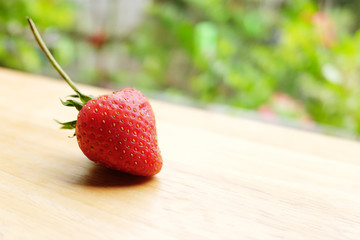 Fresh strawberry on wooden table in natural green background.Copy Space