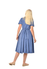 full length portrait of blonde girl wearing blue dress. standing pose with back to the camera. isolated on white  studio background.