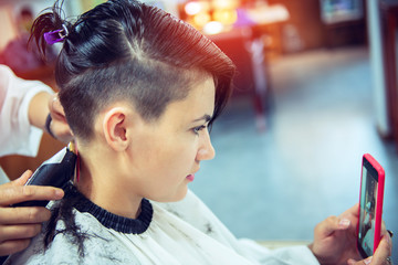 Young woman and hairdresser cuting hair at hairdressing salon. Hairdresser cuts beautiful girl's...