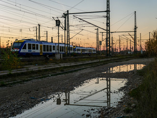 Railway sunset scene with train and water reflections