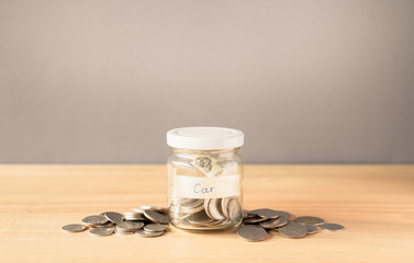Coin in a glass jar on wooden desk with copy space, Saving money for buy a car concept