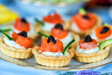 Tartlets with cheese, salmon and olives close