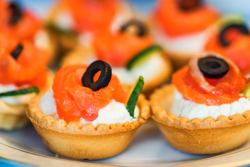 Tartlets with cheese, salmon and olives close