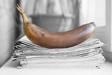 Stack of newspapers and banana. Daily journals with headlines and articles and rotten fruits....