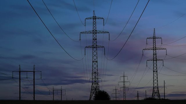 Electricity pylons and the evening sky on the background. Timelapse. Zoom out 4K