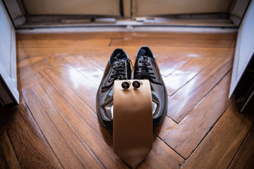 Fototapeta na wymiar Detail of the groom's shoes, tie and cufflinks on his wedding day near the window