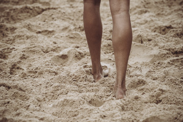 Fototapeta na wymiar Close up of female legs walking by the beach.