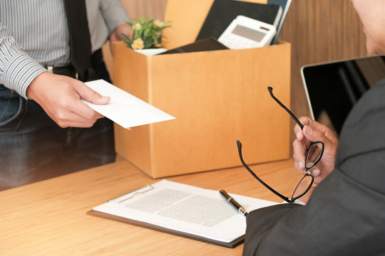 Business Man Sending Resignation Letter To Boss And Holding Stuff Resign Depress Or Carrying Cardboard Box By Desk In Office.