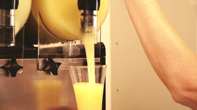 Hand pouring a frozen lemon slush in a store.