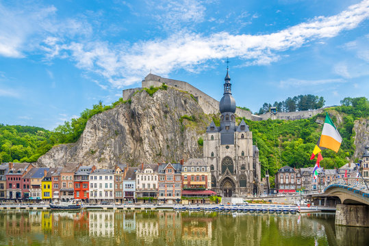 View at the embankment of Meuse river with houses and church of Our Lady Assumption in Dinant - Belgium