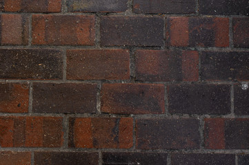 Exterior wall with lines of concrete between brown and black building bricks