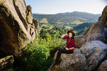 Naklejka premium Young beautiful woman witn vintage photocamera on the rocky mountains with scenic landscape on the background