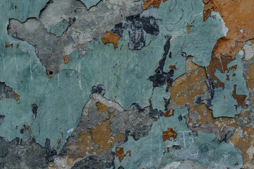 Old dilapidated exterior concrete wall with peeled off multicolor paint