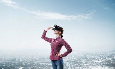Girl in checked shirt wearing VR glasses experiencing another re