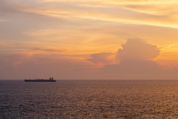 Naklejka na ściany i meble Sunset at the Sea with boat and cloudy sky