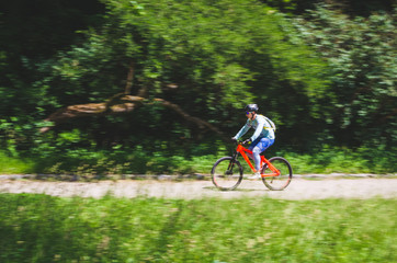 A cyclist in a helmet rides a bicycle path, motion blur