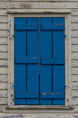 Fototapeta na wymiar Colorful and weathered wooden shutters on old cottage