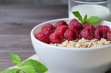 Healthy vegetarian food. Oatmeal with raspberryand mint leaves. Brown wooden background.