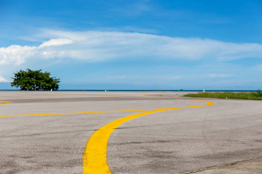 yellow line on taxiway at airfield with sea and blue sky background