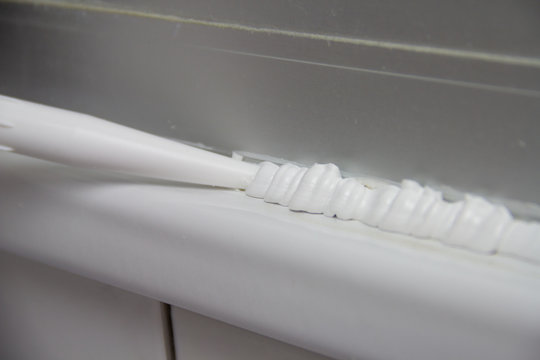 Heimwerker fertigt beim Renovieren mit einer Spritze eine Silikondichtung im Badezimmer f&uuml;r die Dusche