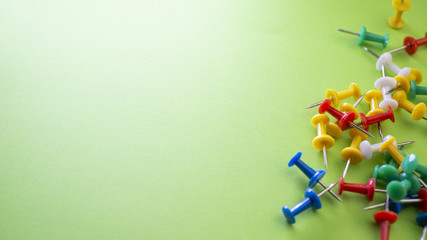 Color push pins on green background for copyspace. Concept of office administrator business,...