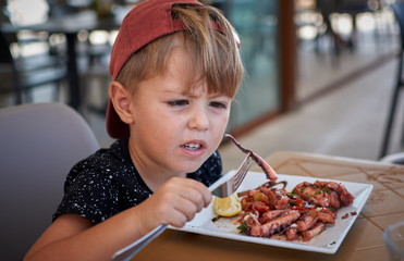 Little boy watching octopus tentacle on his fork