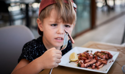 Little boy watching what part of octopus he eating