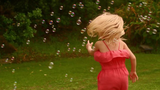 Little girl playing with bubbles in park