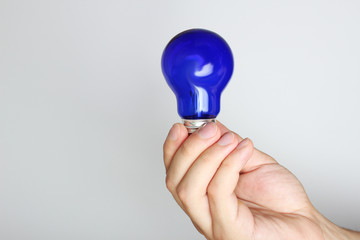 blue light bulb in hand on a light background