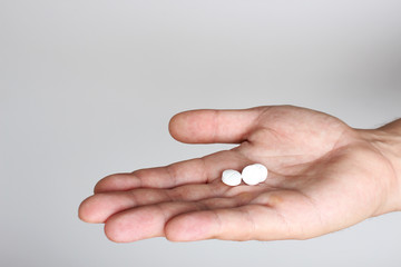 white pills in a hand on a light background
