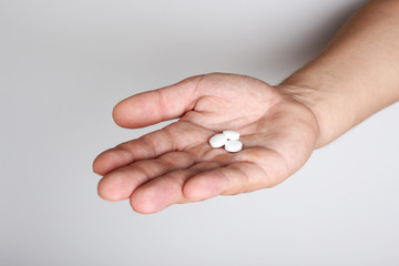 white pills in a hand on a light background