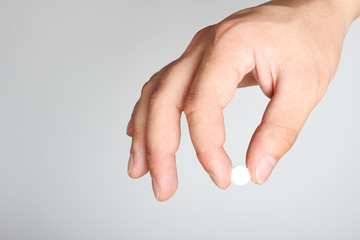 white pills in a hand on a light background