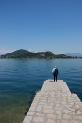 Man in suit in Arona, Lake Maggiore. Rocca di Angera castle in the background, Italy