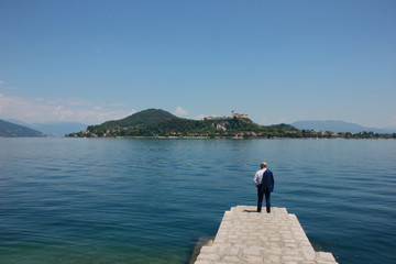 Fototapeta na wymiar Man in suit in Arona, Lake Maggiore. Rocca di Angera castle in the background, Italy