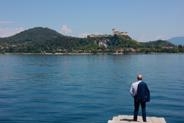 Uomo guarda la Rocca di Angera ad Arona, Lago Maggiore, Piemonte, Italia