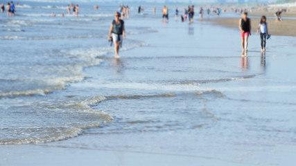 Beach holiday with people strolling in shallow water (with blur effect)