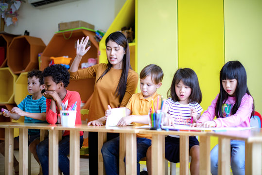 woman teacher in classroom teaching preschool kids, joyful learning together with mixed-race international children