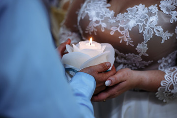 The bride and groom hold a burning candle in the form of a rose