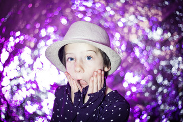 Young short hair girl with fashion hat is surprised and has big blue eyes in front of pink background with copy space for text