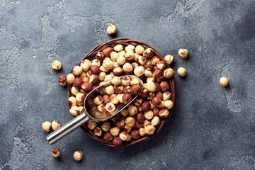 Hazelnuts and scoop on gray background