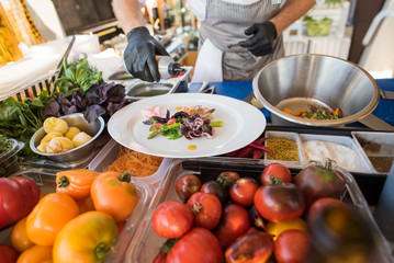 A cook preparing delicious dish with little octopuses at the open air restaurant