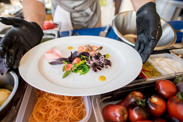 A cook preparing delicious dish with little octopuses at the open air restaurant